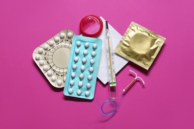 Contraceptive pills, condoms, intrauterine device and thermometer on pink background, flat lay. Different birth control methods