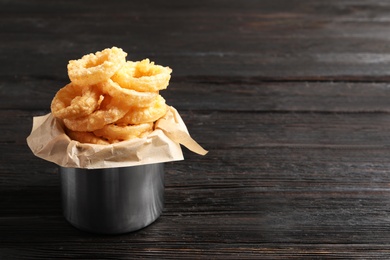 Dishware with homemade crunchy fried onion rings on wooden table. Space for text