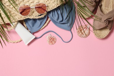 Flat lay composition with wicker bag and other beach accessories on pink background. Space for text