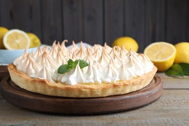 Photo of Delicious lemon meringue pie decorated with mint on wooden table