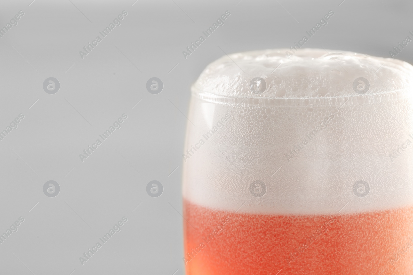 Photo of Glass of red tasty beer with foam, closeup