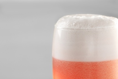 Photo of Glass of red tasty beer with foam, closeup