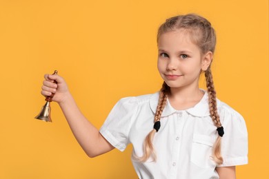 Photo of Pupil with school bell on yellow background