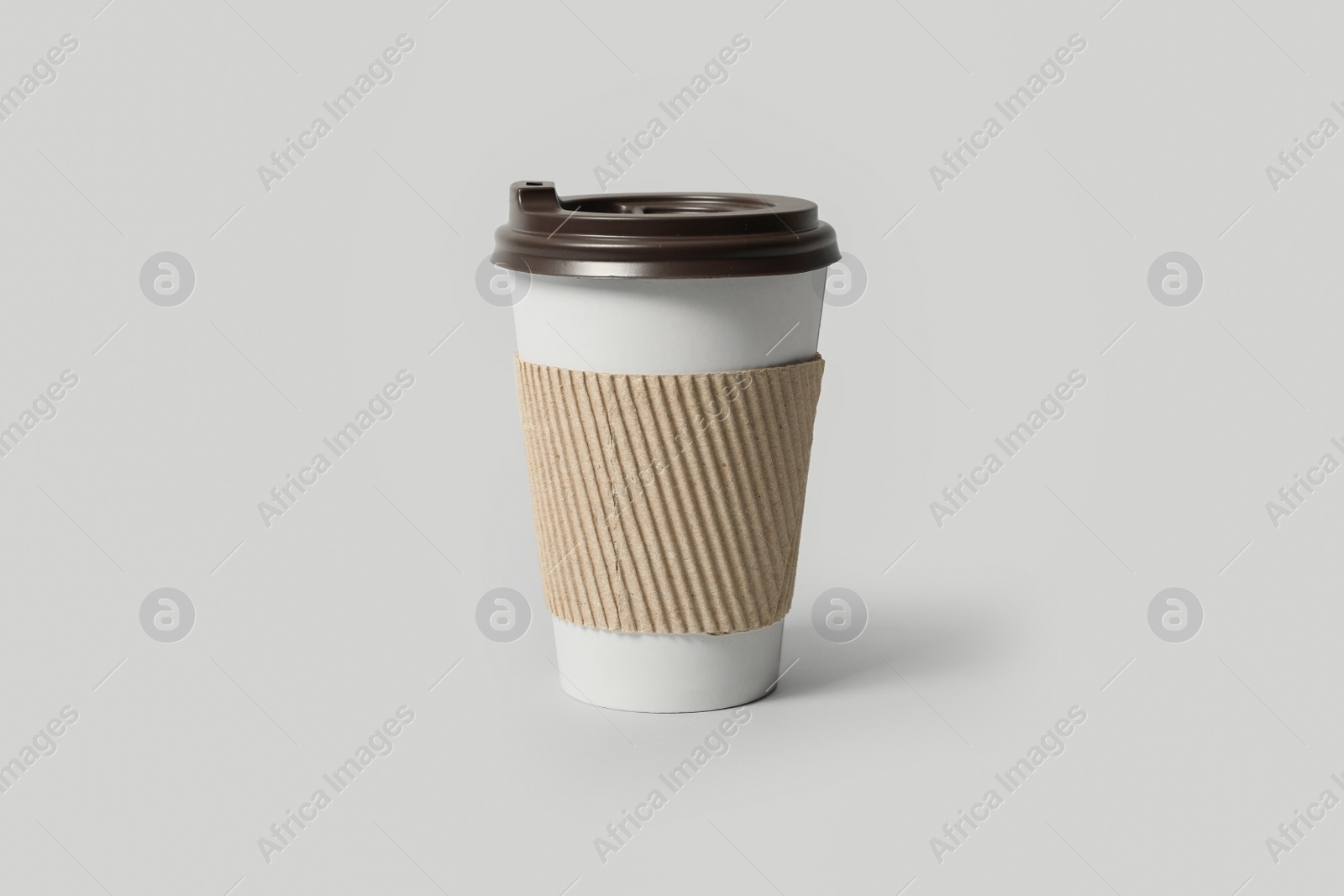 Photo of Takeaway paper coffee cup with cardboard sleeve on light grey background