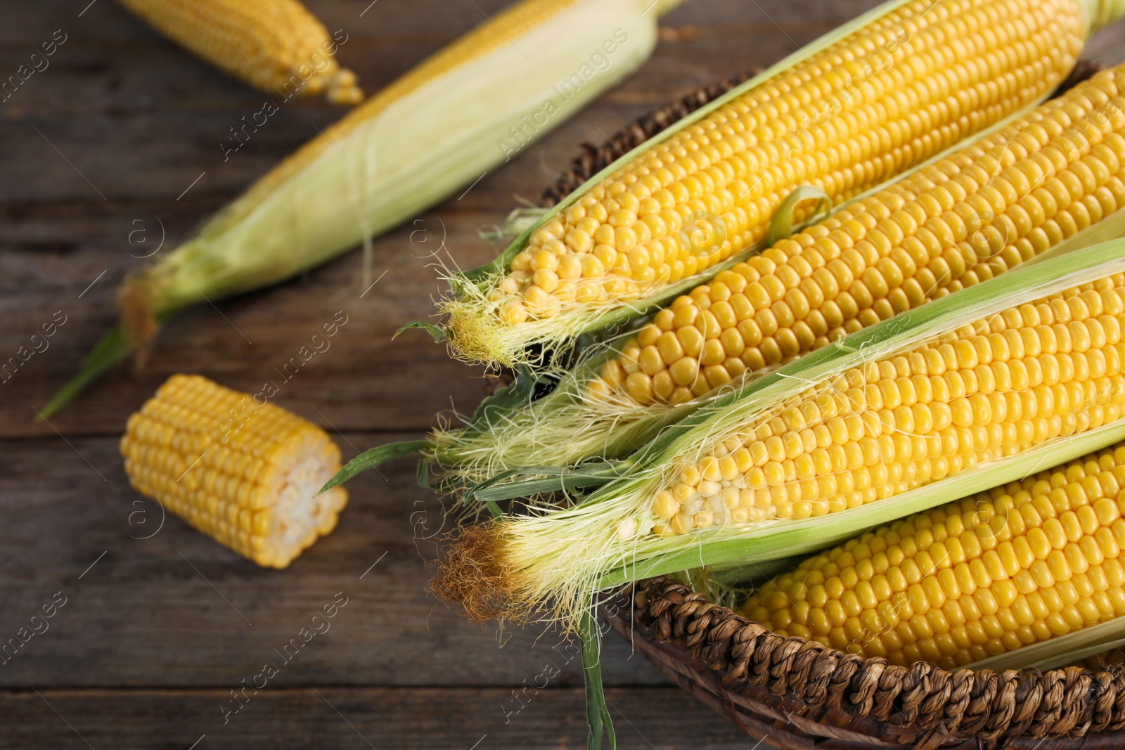 Photo of Basket with tasty sweet corn cobs on table, closeup