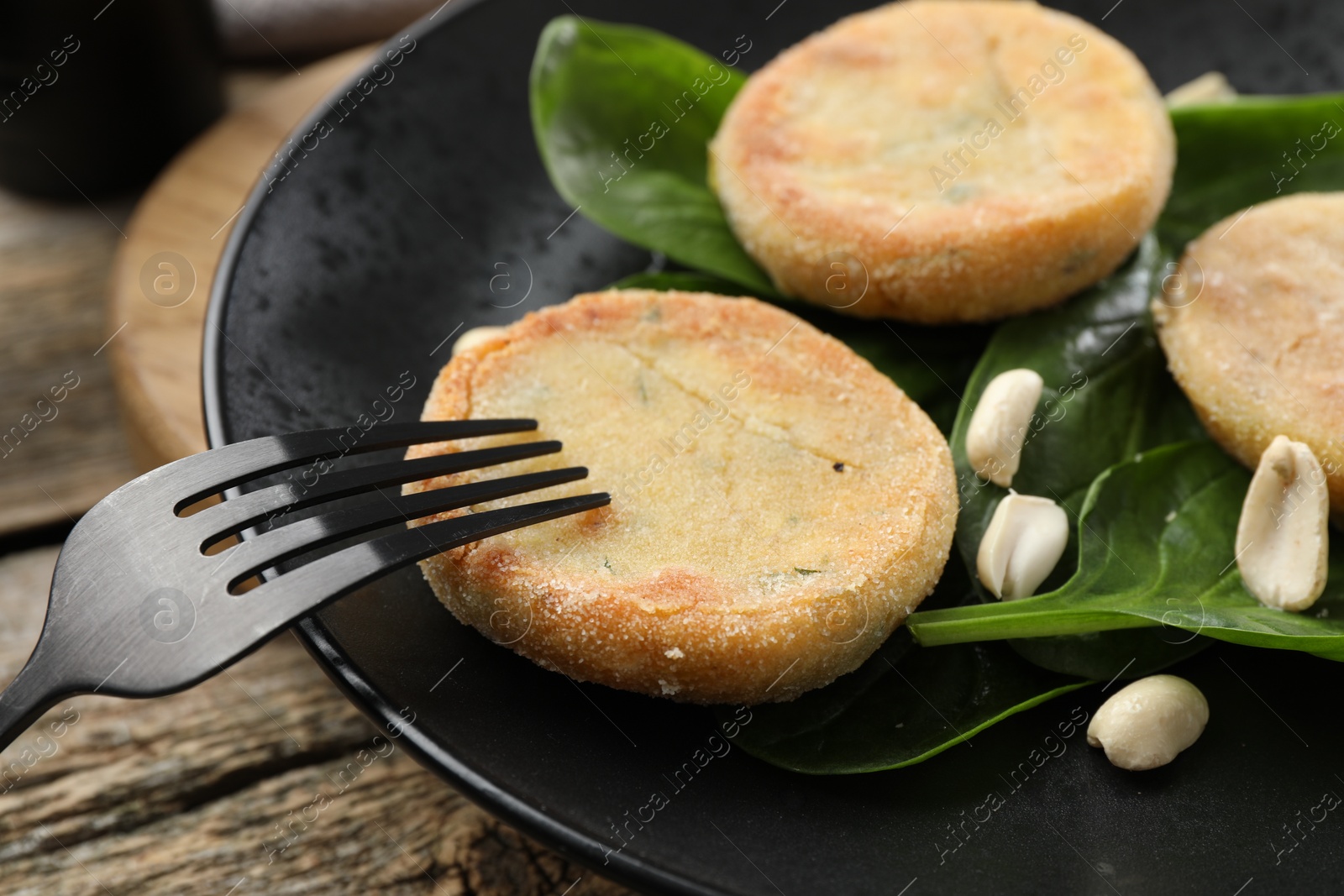 Photo of Plate with healthy dish high in vegetable fats and fork on wooden table, closeup