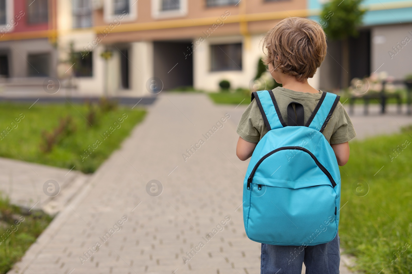 Photo of Little boy walking to kindergarten outdoors, back view. Space for text