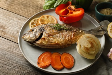 Photo of Delicious dorado fish with vegetables served on wooden table