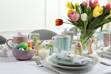 Photo of Easter celebration. Festive table setting with beautiful flowers and painted eggs