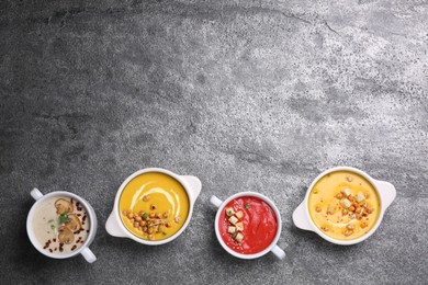 Photo of Different tasty cream soups on grey table, flat lay. Space for text