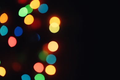Photo of Blurred view of colorful lights on black background, space for text