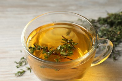 Photo of Cup of fresh thyme tea on table, closeup