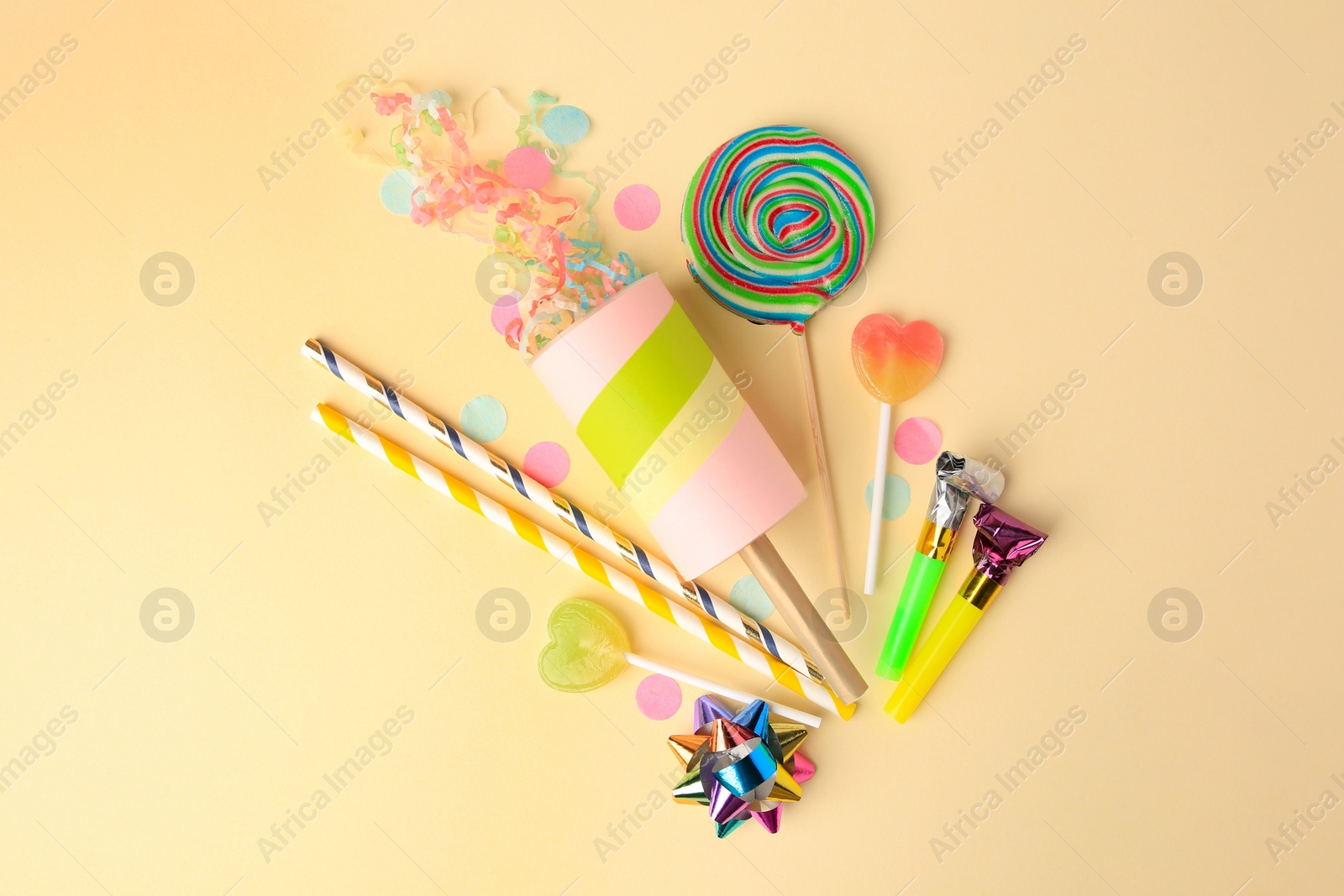 Photo of Party cracker and different festive items on beige background, flat lay