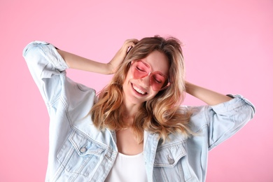 Photo of Young beautiful woman wearing heart shaped glasses on pink background