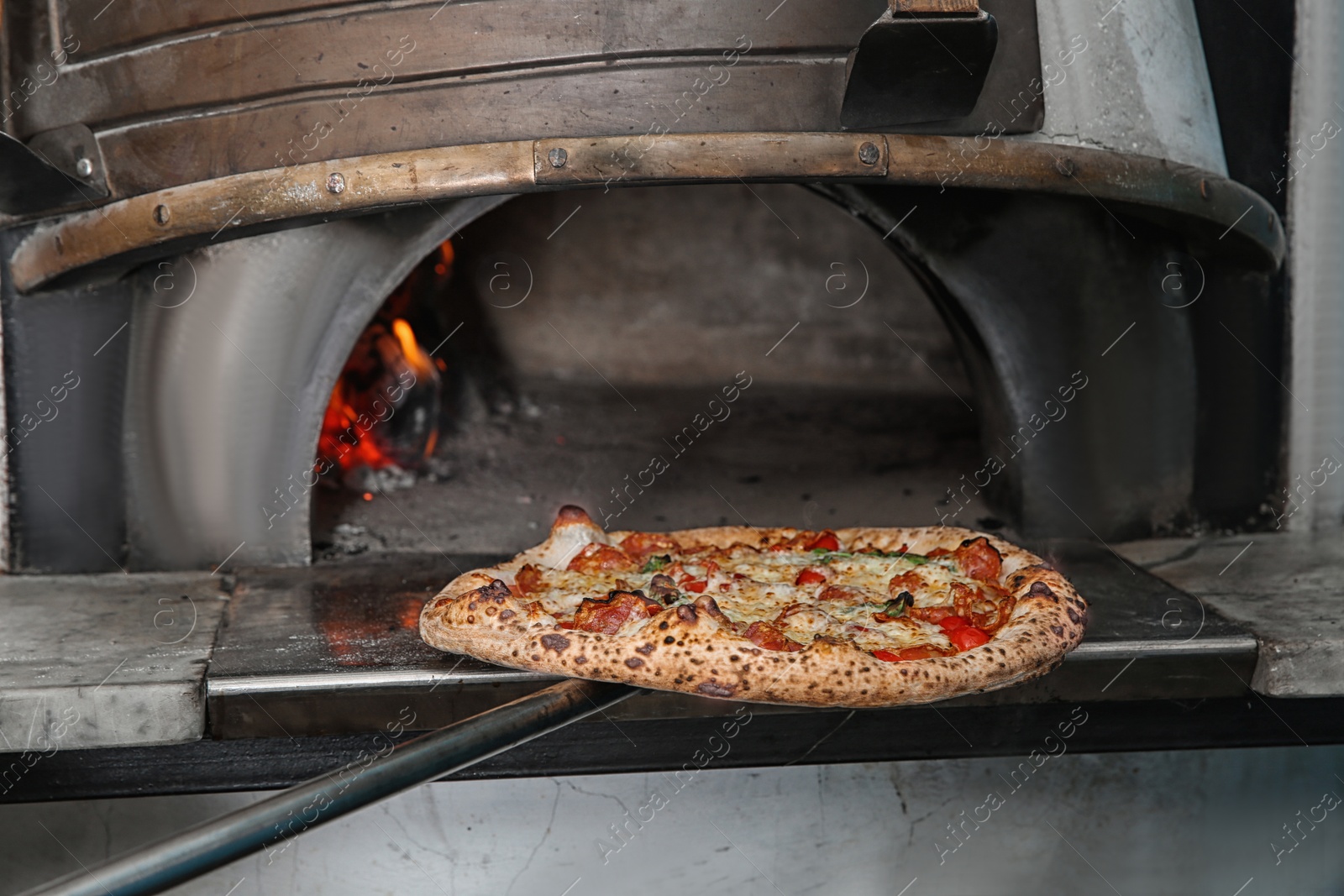 Photo of Taking out tasty pizza from oven in restaurant kitchen