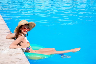 Photo of Happy young woman with inflatable ring in swimming pool