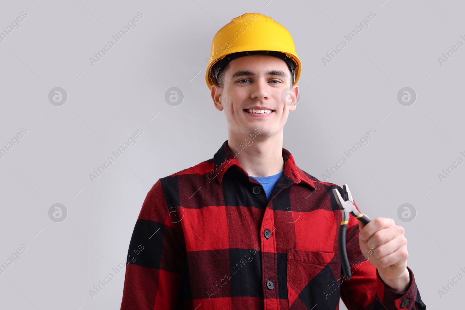 Photo of Young man holding pliers on grey background