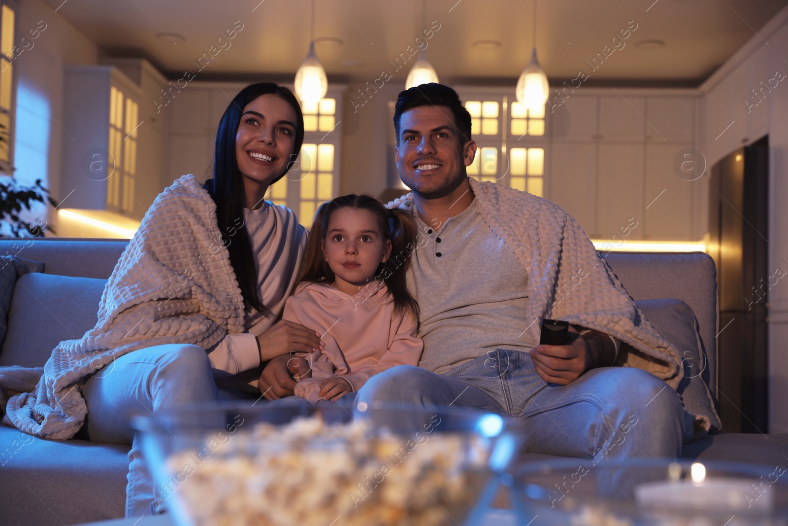 Photo of Family watching movie on sofa at night