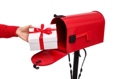 Photo of Woman putting Christmas gift into mailbox on white background, closeup. Sending present by mail