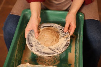 Woman crafting with clay on potter's wheel, closeup