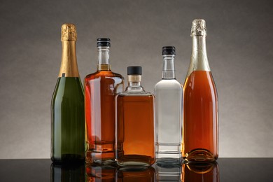 Bottles of different alcoholic drinks on table against gray background