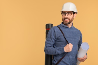 Photo of Architect in hard hat with drawing tube and draft on beige background, space for text