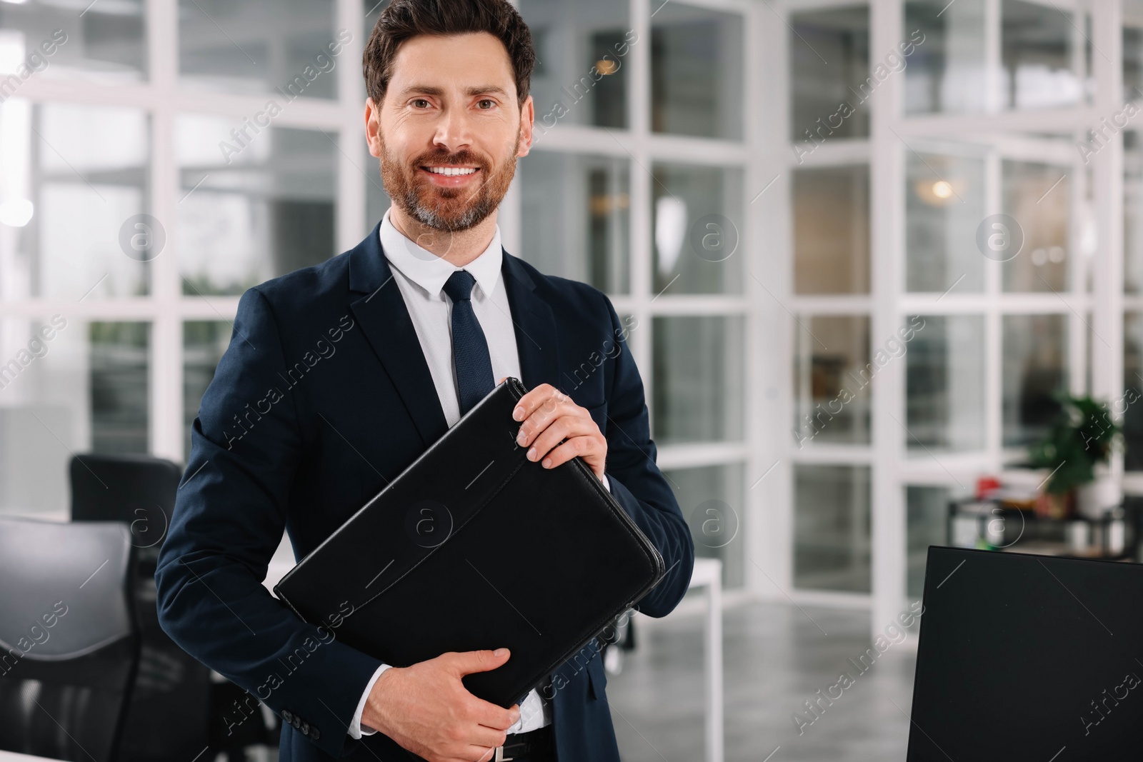 Photo of Happy real estate agent with leather portfolio indoors. Space for text