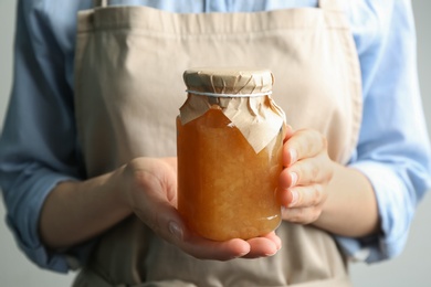 Photo of Woman with jar of delicious pear jam, closeup