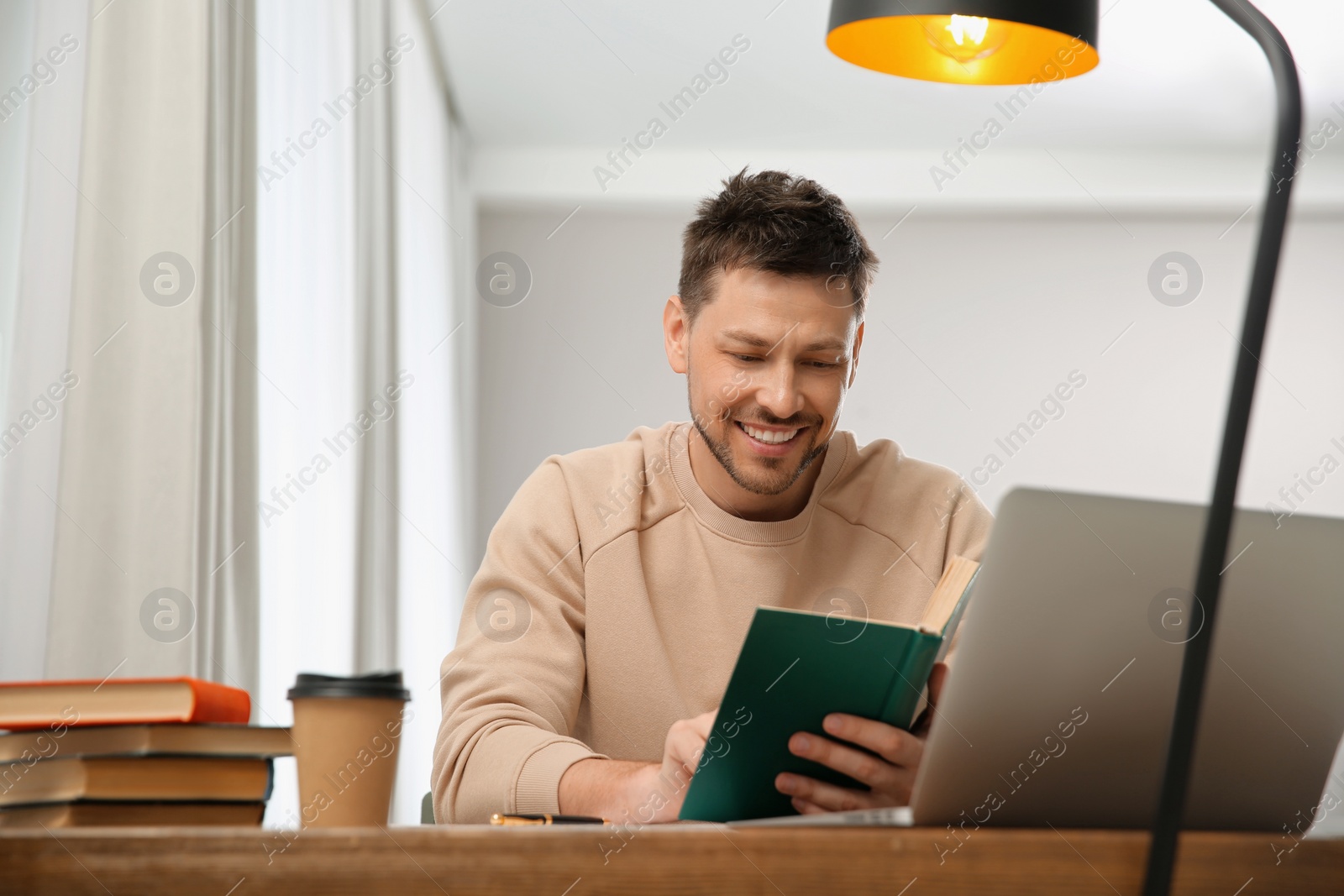 Photo of Man reading book at table in library