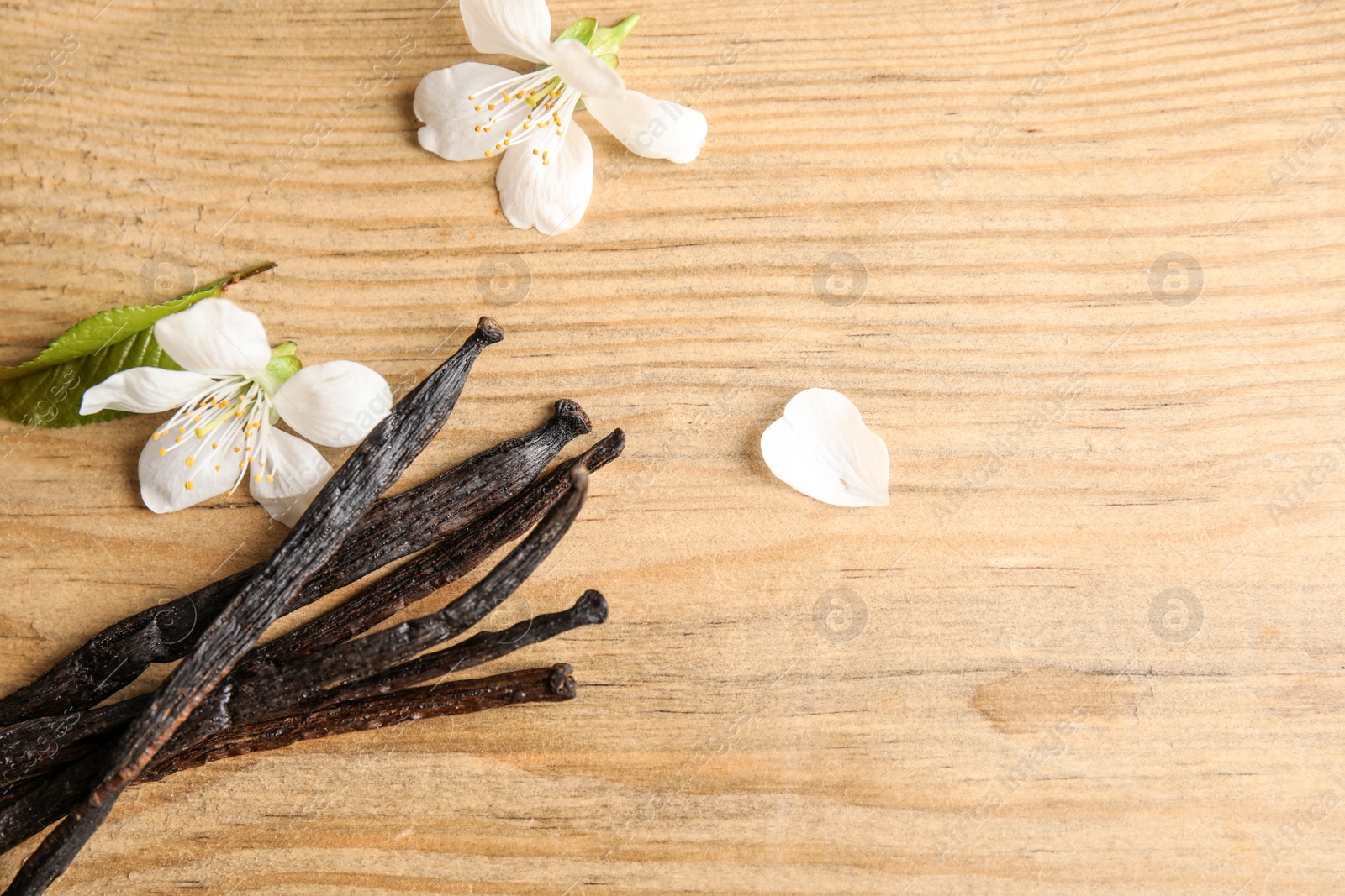 Photo of Flat lay composition with aromatic vanilla sticks and flowers on wooden background. Space for text