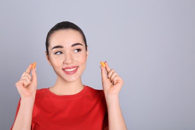 Photo of Young woman with foam ear plugs on grey background. Space for text