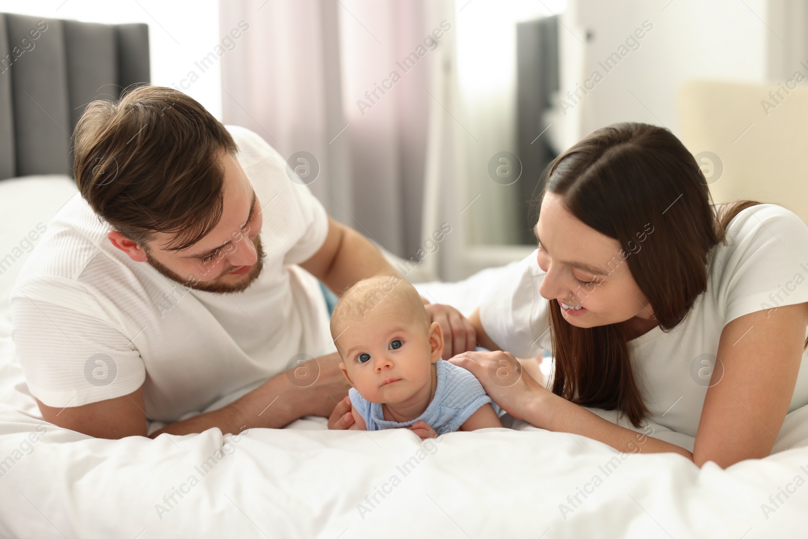 Photo of Happy family. Parents with their cute baby on bed indoors