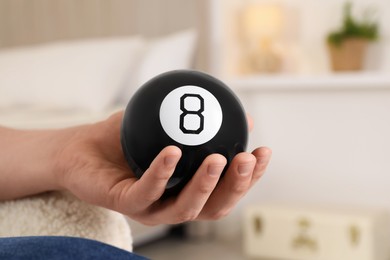 Photo of Man holding magic eight ball indoors, closeup