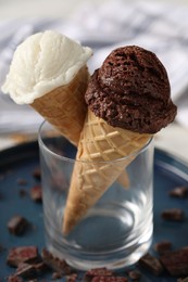 Photo of Tasty ice cream scoops in waffle cones and chocolate crumbs on table, closeup
