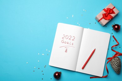 Photo of Open planner and Christmas decor on light blue background, flat lay with space for text. Planning for 2022 New Year