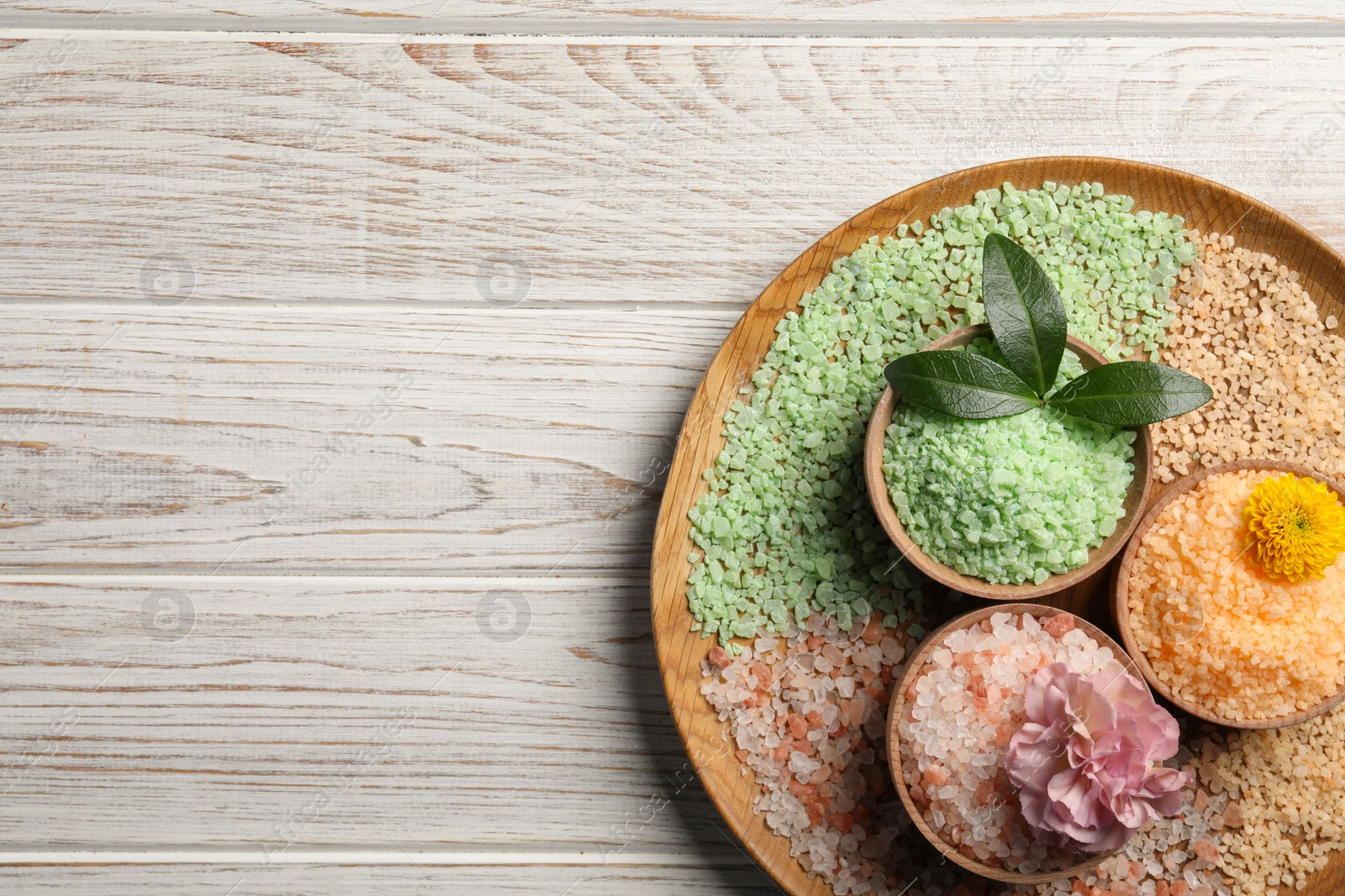 Photo of Different types of aromatic sea salt on white wooden table, top view. Space for text