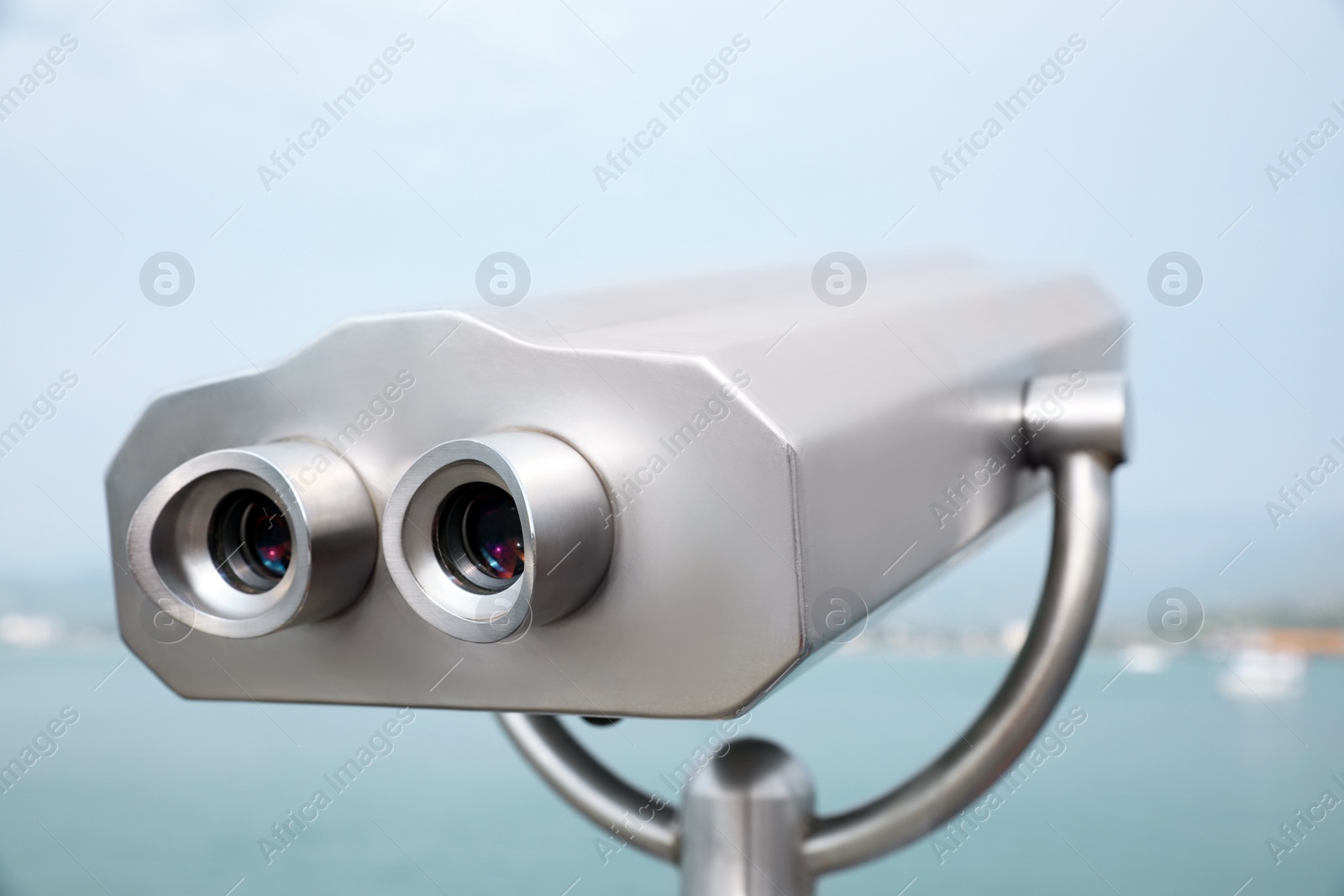 Photo of Metal tower viewer installed near sea. Mounted binoculars