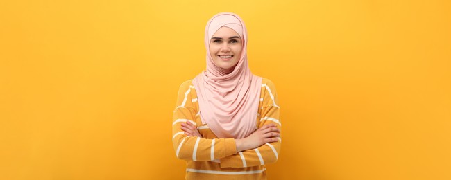 Image of Portrait of Muslim woman in hijab on yellow background. Banner design
