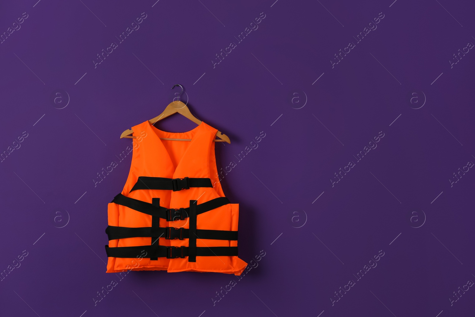 Photo of Orange life jacket on violet background. Space for text