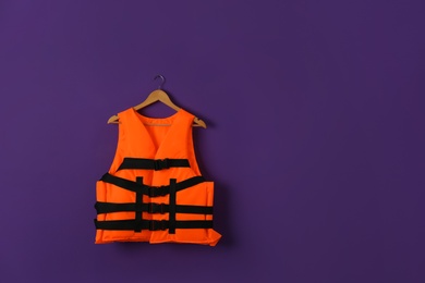 Photo of Orange life jacket on violet background. Space for text