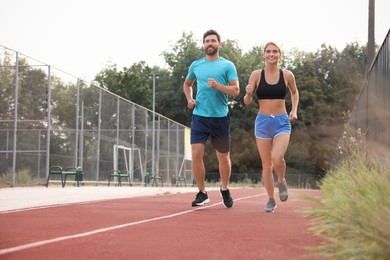 Photo of Healthy lifestyle. Happy sporty couple running at stadium, space for text
