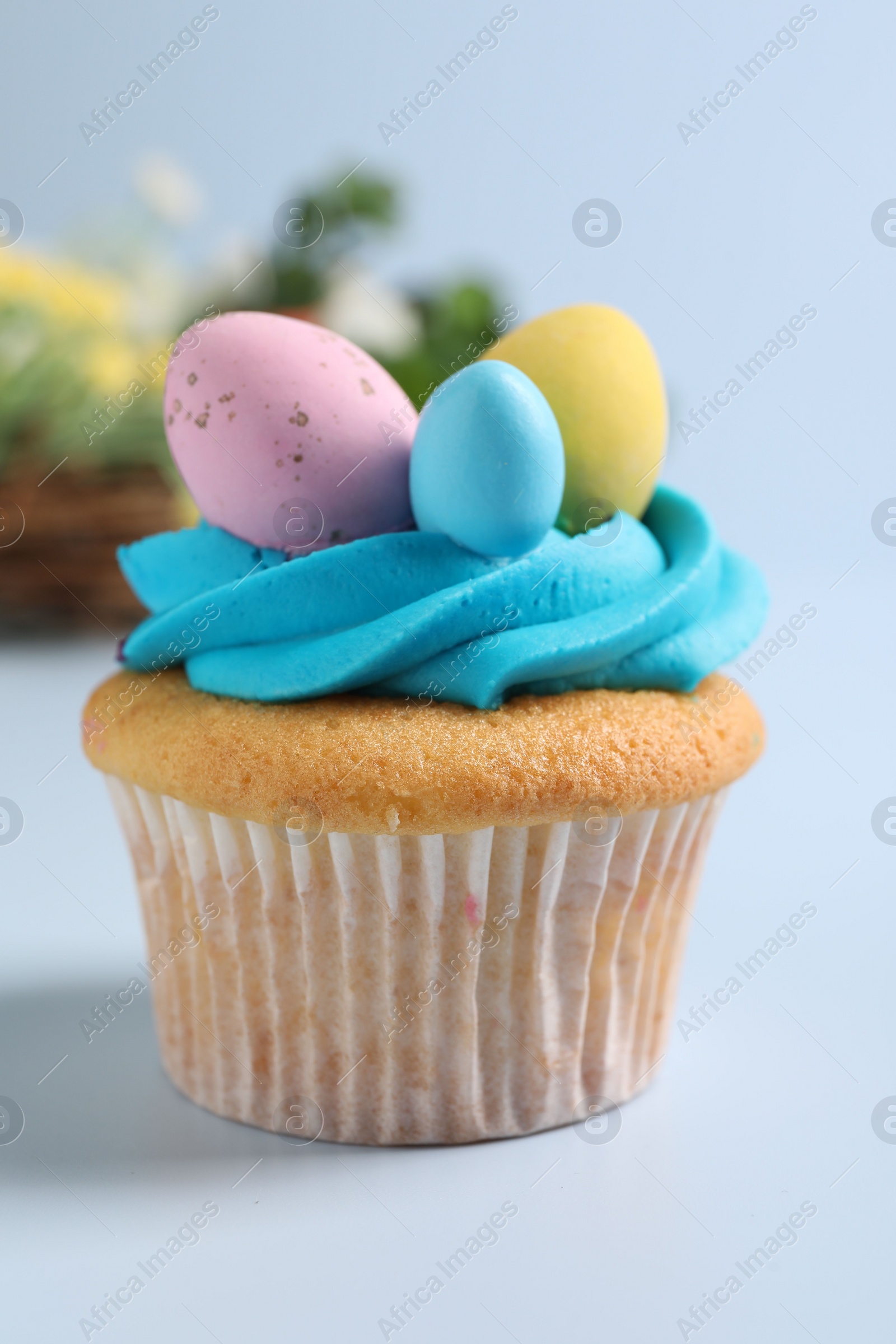 Photo of Tasty decorated Easter cupcake on light blue background, closeup