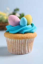 Photo of Tasty decorated Easter cupcake on light blue background, closeup