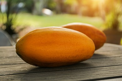 Fresh ripe papaya fruits on wooden table outdoors