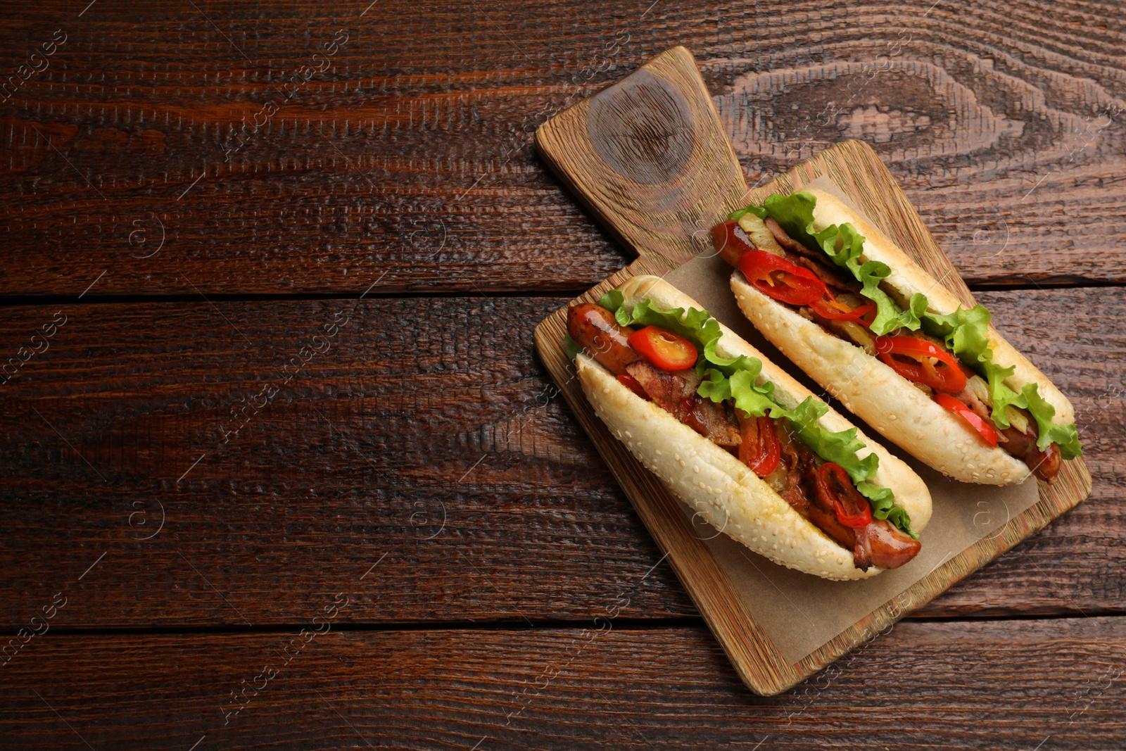 Photo of Tasty hot dogs on wooden table, top view and space for text. Fast food