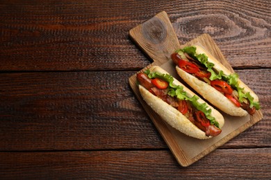 Photo of Tasty hot dogs on wooden table, top view and space for text. Fast food
