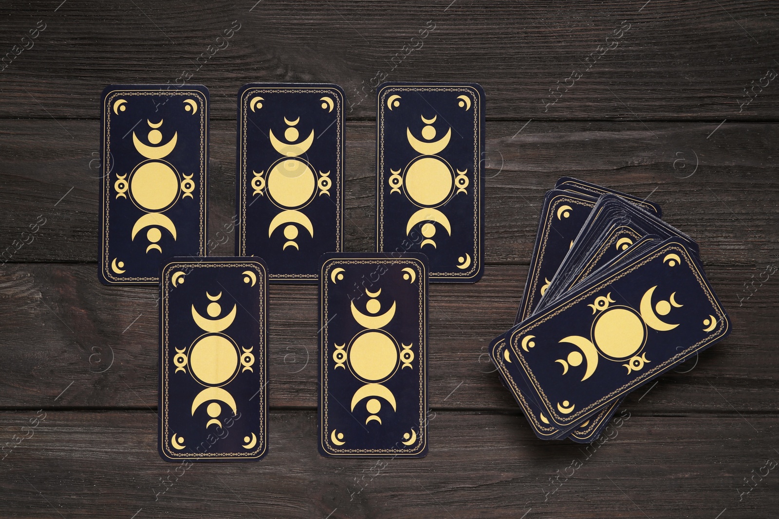 Photo of Tarot cards on black wooden table, flat lay. Reverse side