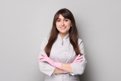 Photo of Cosmetologist in medical uniform on grey background