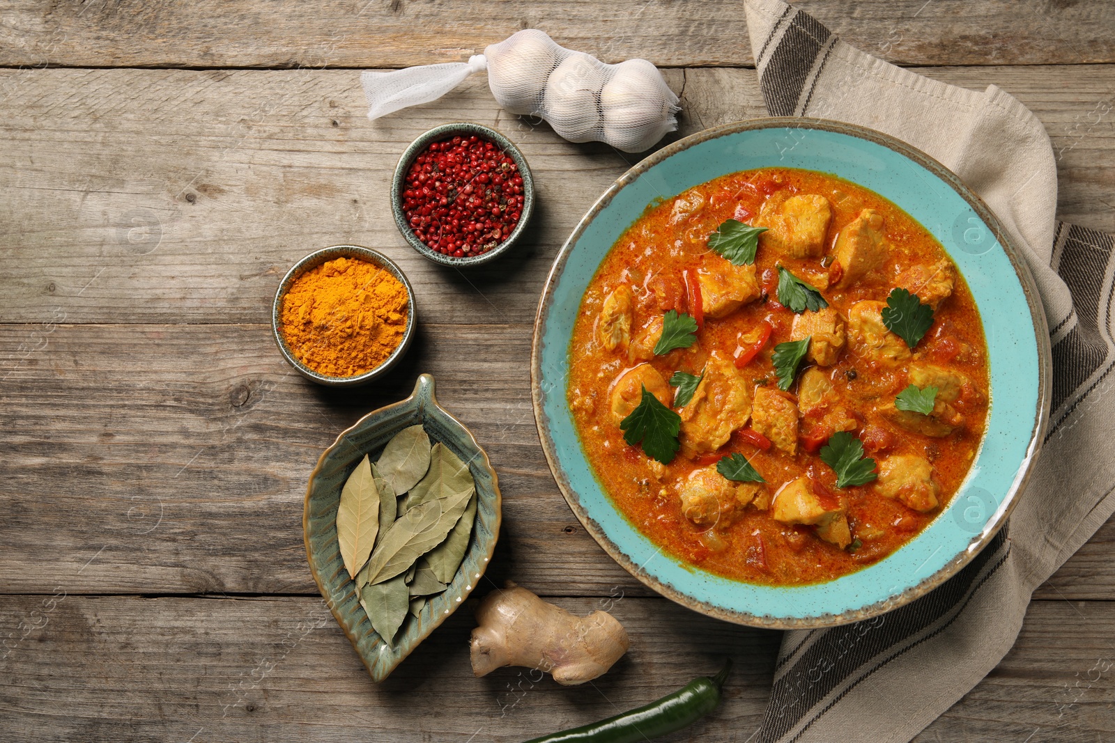 Photo of Delicious chicken curry and ingredients on wooden table, flat lay