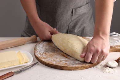 Photo of Man kneading dough at table near grey wall, closeup